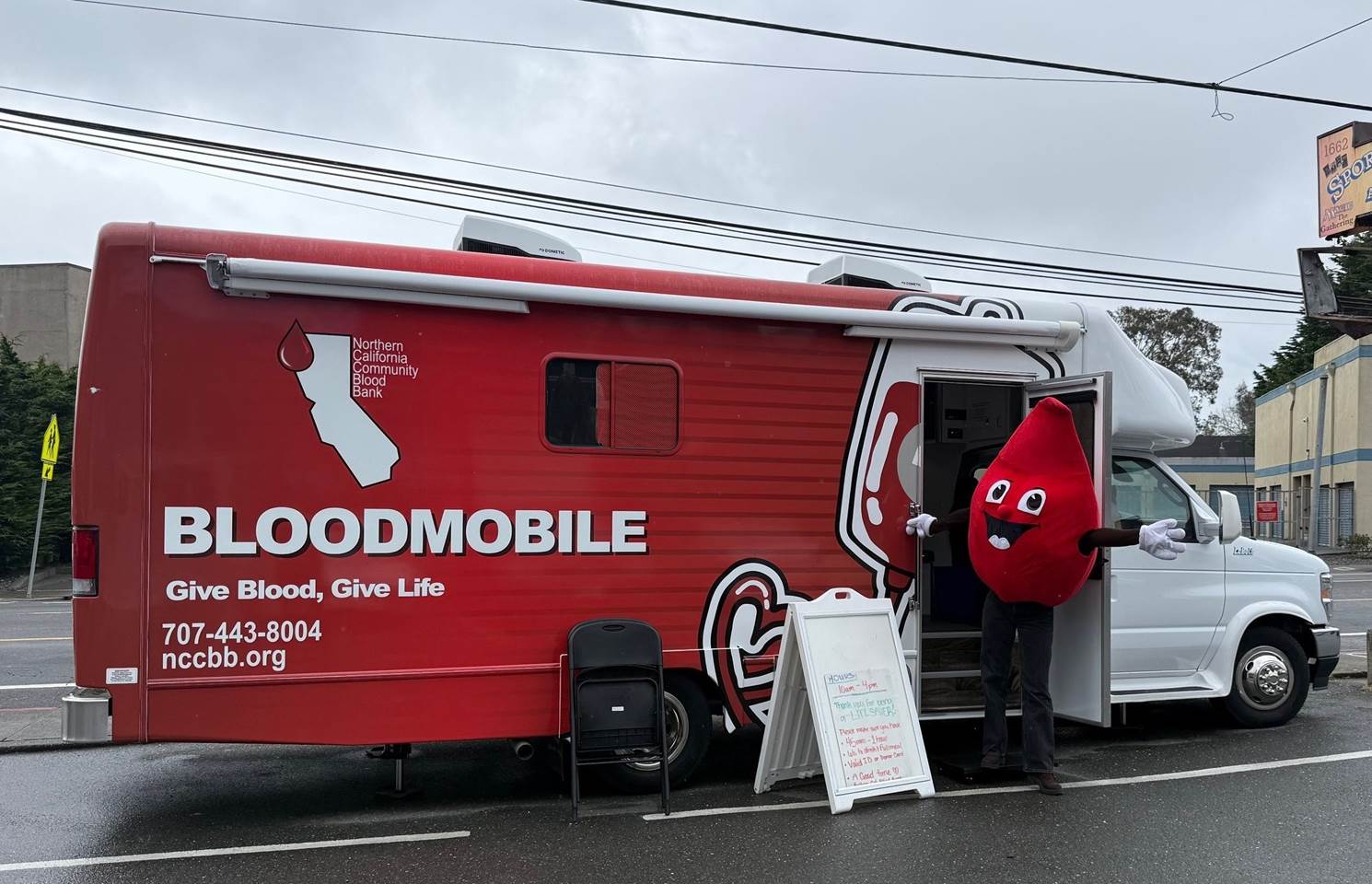Bloodmobile parked in the community with Buddy the mascot